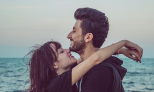 Молодая пара стоит в обнимку на берегу моря