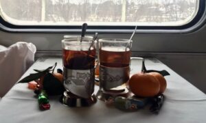 Cups with tea, tangerines, and candy on the table in the train