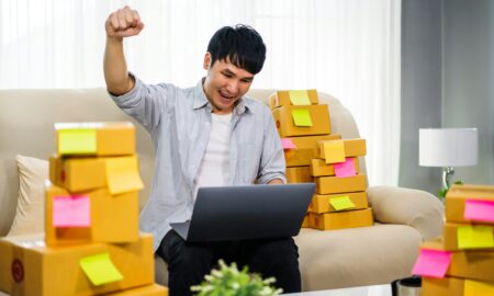 Мужчина в офисе сидит с ноутбуком и радуется