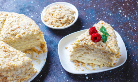 Домашний торт Наполеон на тарелке, украшенный ягодой