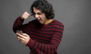 Мошенник кричит на телефон после того, как ему не удалось провести абонента на деньги