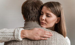 Женщина обнимает мужчину, сдвинув брови