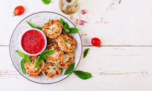 Аппетитные творожные сырники с зеленью и соусом в тарелке