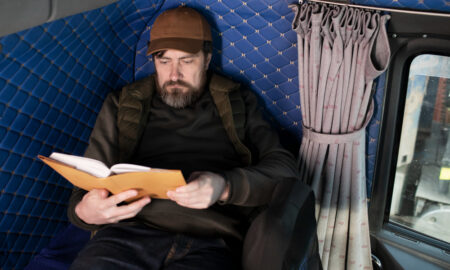 Мужчина читает книгу на полке в поезде