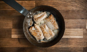 Pieces of white fish are fried on the hot pan with butter