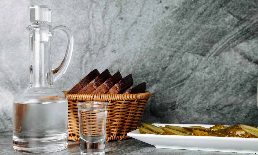 Алкоголь, хлеб и огурец на столе