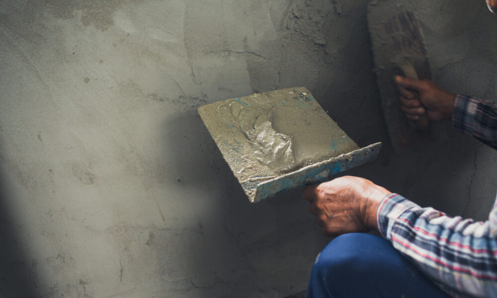 Штукатур ровняет стену