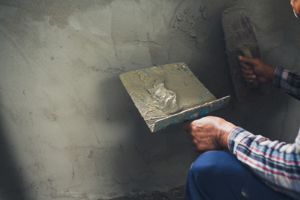 Штукатур ровняет стену