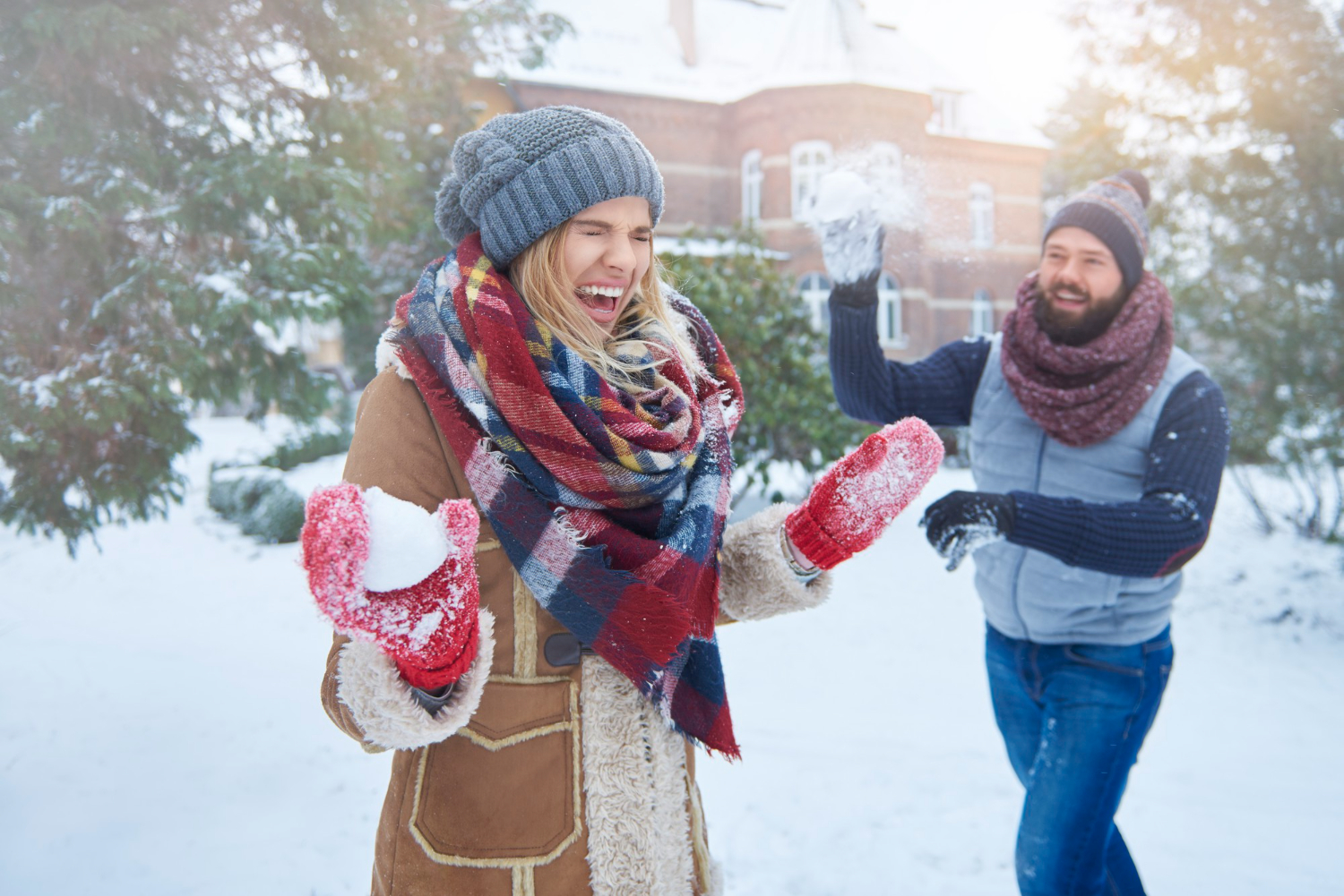 Мужчина бросает снежок в смеющуюся женщину
