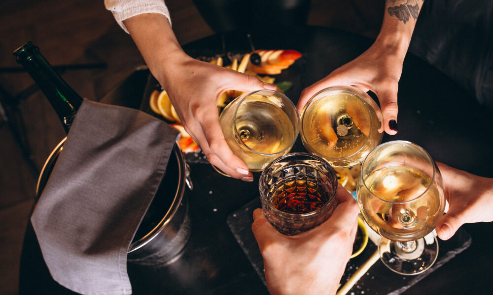 Люди чекаются бокалами с дорогим алкоголем