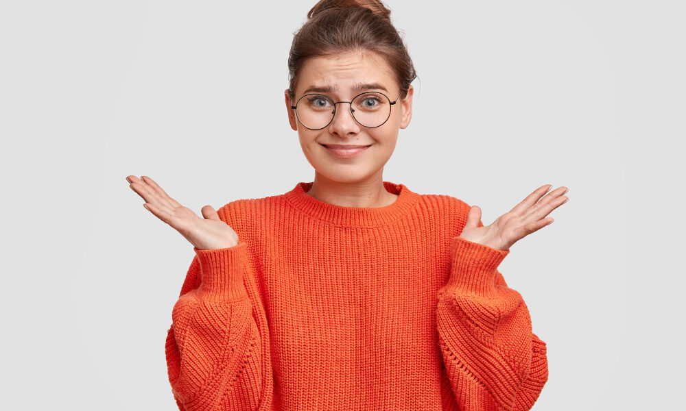 девушка в красной кофте и очках не понимает