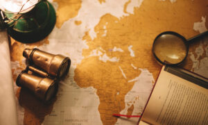 Бинокль и лупа лежат рядом с картой мира