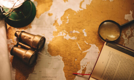 Бинокль и лупа лежат рядом с картой мира