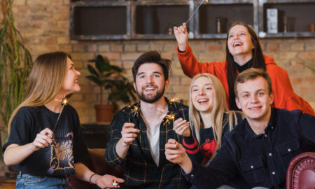 Компания друзей веселиться вместе и держат бенгальские огоньки