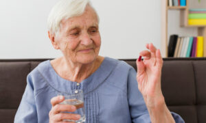 Пожилая женщина принимает таблетки