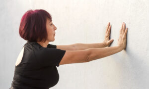Женщина отжимается от стены