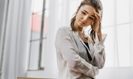 Сосредоточенная девушка стоит у окна