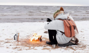 Турист сидит на пляже зимой