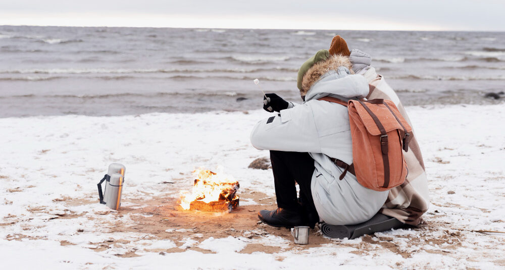 Турист сидит на пляже зимой