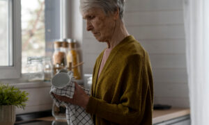 Старая женщина протирает кружку полотенцем