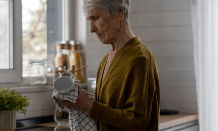 Старая женщина протирает кружку полотенцем