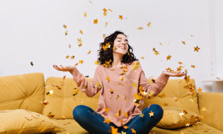 Счастливая девушка сидит на диване, сыплются золотые конфетти