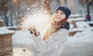Девушка играет со снегом в солнечный зимний день