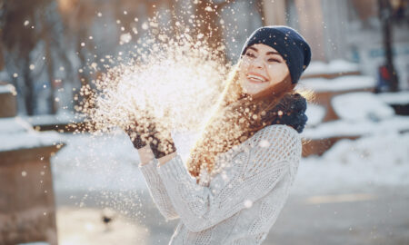 Девушка играет со снегом в солнечный зимний день