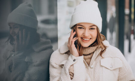 Женщина в шапке и куртке говорит по телефону