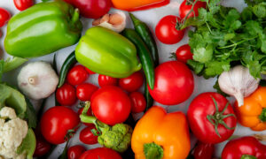 Разные овощи красиво лежат на столе, есть тут перцы, чеснок, помидоры, грибы.