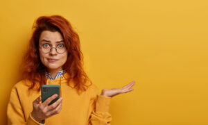 Рыжая девушка на желтом фоне решает задачки