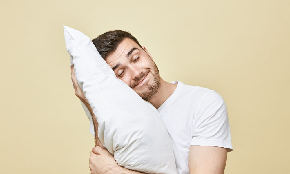 Мужчина обнимает подушку на желтом фоне