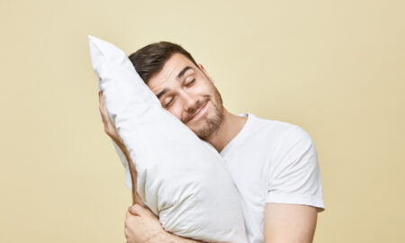 Мужчина обнимает подушку на желтом фоне