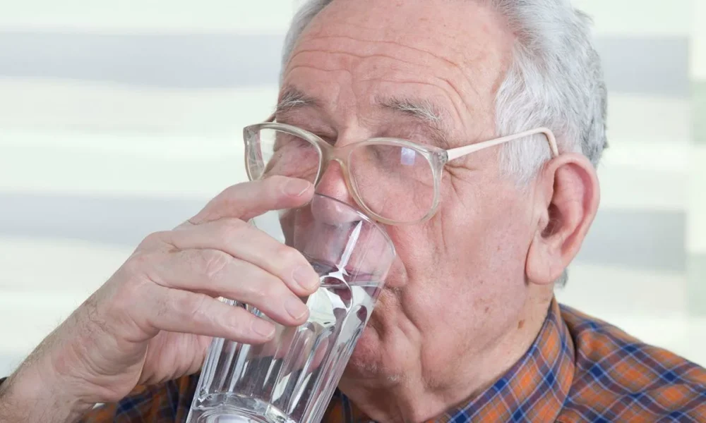 Пожилой мужчина пьет воду