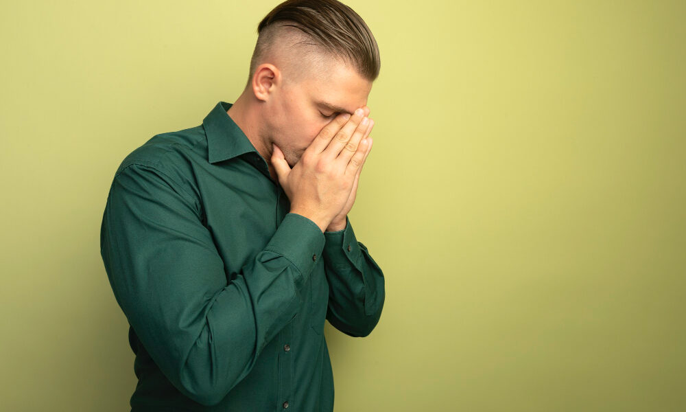 Парень в зеленом свитере чихает