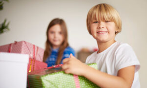 Мальчик и девочка распаковывают подарки.