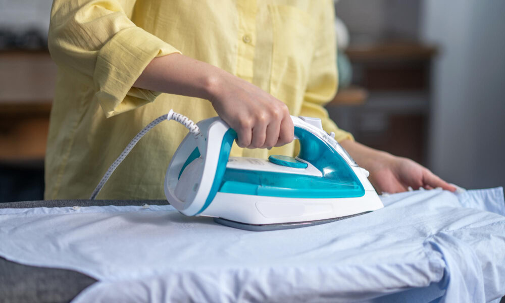 Девушка гладит одежду утюгом