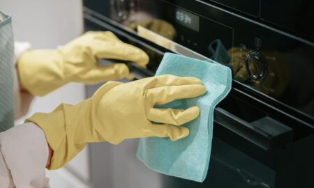 Девушка моет духовку тряпкой