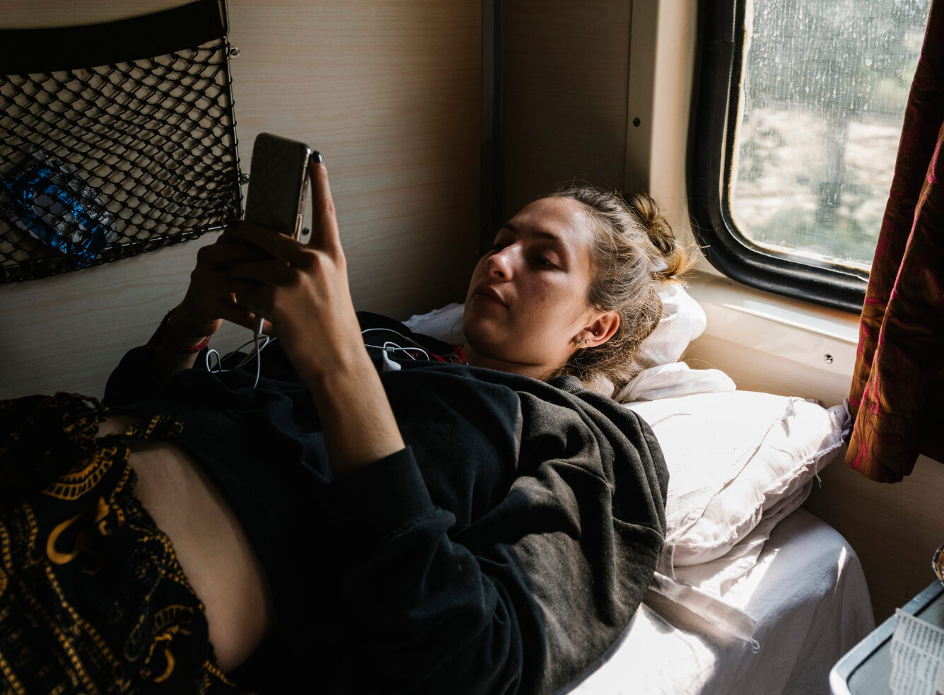Девушка лежит на полке в вагоне поезда