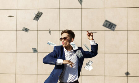 Мужчина в очках радуется денежным купюрам