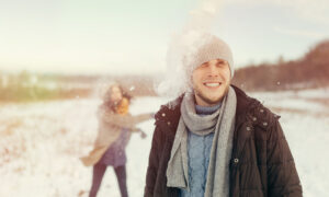 Девушка и парень играют в снежки зимой