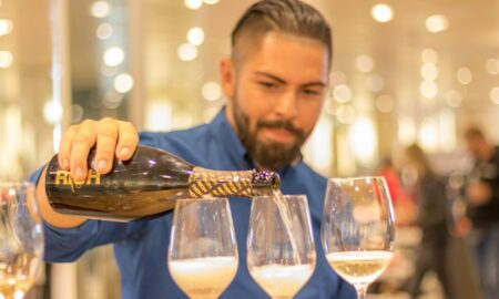 Разливает вино по бокалам