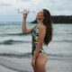 Девушка в купальнике пьет воду на пляже
