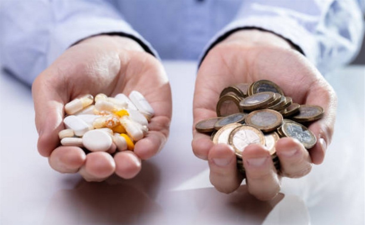 Таблетки и деньги в руках у человека