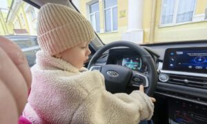 Ребенок сидит за рулем автомобиля.