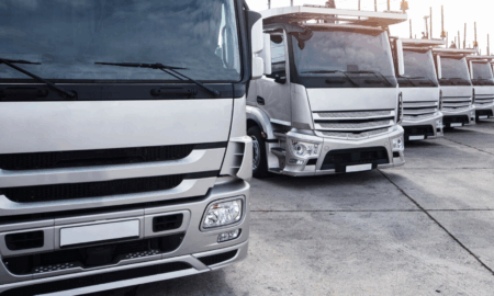 Крупные грузовые автомобили стоят перед выездом на дорогу