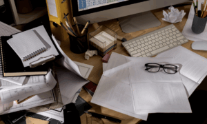 Рабочий стол, на котором есть разные канцелярские принадлежности и бумага