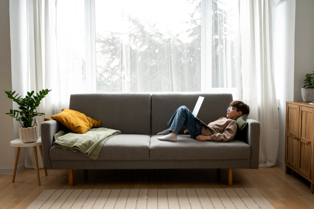 Ребёнок лежит на диване с компьютером