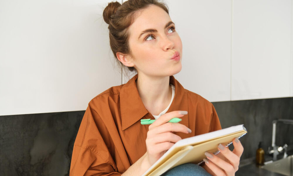 Женщина с блокнотом сидит на кухне