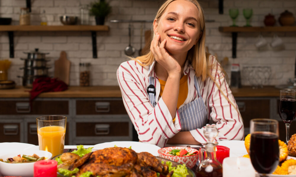 девушка сидит за столом с готовой едой и улыбается